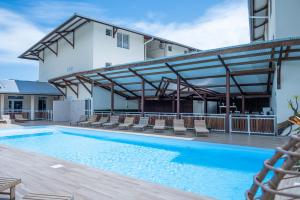 une piscine avec des chaises et un bâtiment dans l'établissement Hôtel Belle Terre Resort, à Macouria