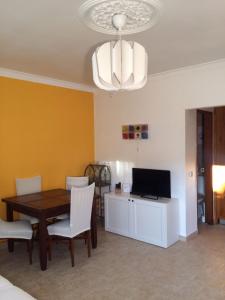 uma sala de jantar com uma mesa e uma televisão em Caparica Holidays em Charneca