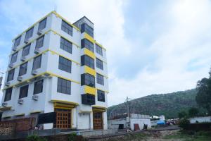 un bâtiment blanc et jaune avec une colline en arrière-plan dans l'établissement Hotel Gridhakuta International, à Rajgir