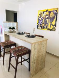 a kitchen with a large wooden counter with two stools at Apartamento Praia de Porto Belo, Balneario Pereque, SC in Porto Belo