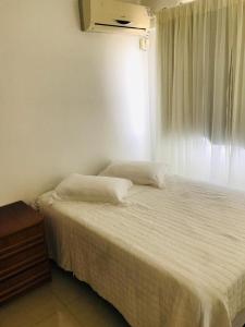 a bedroom with a white bed with a window at Apartamento Praia de Porto Belo, Balneario Pereque, SC in Porto Belo