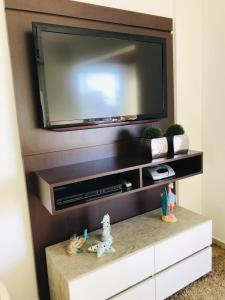 a flat screen tv on a wall above a tv stand at Apartamento Praia de Porto Belo, Balneario Pereque, SC in Porto Belo