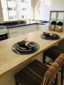 a wooden table with two plates and a wine glass at Apartamento Praia de Porto Belo, Balneario Pereque, SC in Porto Belo