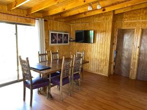 ein Esszimmer mit einem Holztisch und Stühlen in der Unterkunft Cabañas y Centro Eventos Leyda in San Antonio
