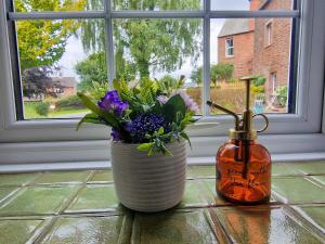 a vase with flowers in it next to a window at Mickledale at Wetheral Cottages in Great Salkeld