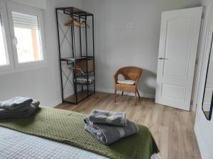 1 dormitorio con 1 cama con manta verde y silla en Ortegal Beach & Seacliffs, en Cariño
