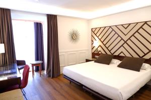 a bedroom with a large white bed and a window at Hotel Boutique Atrio in Valladolid