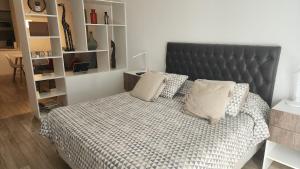 um quarto com uma cama com uma cabeceira e almofadas pretas em Fabuloso departamento con todo y cerca de todo em Buenos Aires