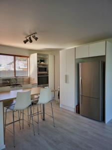 a kitchen with a table and chairs and a refrigerator at Oceanside Haven in Ohope Beach