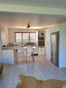 cocina con mesa, sillas y nevera en Oceanside Haven en Ohope Beach