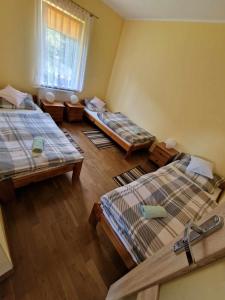 Zimmer mit 3 Betten, einem Fenster und Holzböden in der Unterkunft Lochówka - zaciszny domek w górach in Krynica-Zdrój