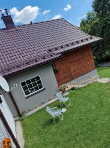 zwei Gartenstühle und ein Haus mit Dach in der Unterkunft Lochówka - zaciszny domek w górach in Krynica-Zdrój