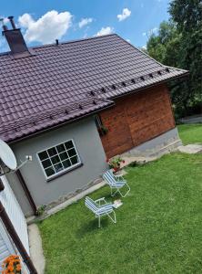 two lawn chairs and a house with a roof at Lochówka - zaciszny domek w górach in Krynica Zdrój