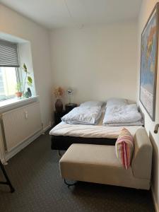 1 dormitorio con 2 camas, silla y ventana en Skøn centralt beliggende lejlighed m.tagterrasse, en Herning