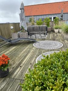 un patio con sillas y una sombrilla en una terraza de madera en Skøn centralt beliggende lejlighed m.tagterrasse en Herning