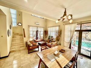 uma ampla sala de estar com uma mesa de madeira e cadeiras em kuta 5BR private villa pool ,near airport, em Kuta