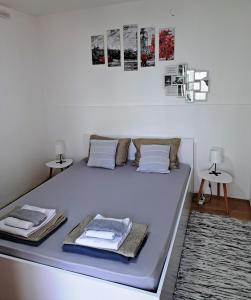 een witte slaapkamer met een bed met 2 tafels bij Anja Apartman in Novi Sad
