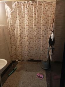 un bagno con tenda per la doccia e 2 pantofole rosa di Ain sbaa Hay mohmmadi a Casablanca
