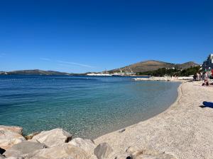 a beach with rocks and the ocean on a clear day at Apartments Villa Mirella 20 m from the sea - free parking in Trogir