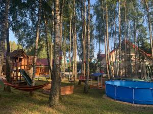 een speeltuin met schommels en een huis in het bos bij Pensjonat Leśny Dworek SPA & Garden Uzdrowisko wśród Natury in Cisów