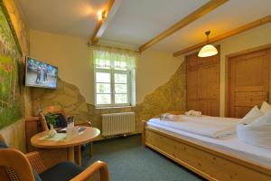 Schlafzimmer mit einem Bett, einem Tisch und einem TV in der Unterkunft Gasthof Ungerberg in Neustadt in Sachsen