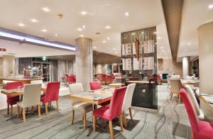 a restaurant with wooden tables and red chairs at Holiday Inn Express Durban - Umhlanga by IHG in Durban