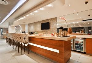 a restaurant with a bar with stools and a tv at Holiday Inn Express Durban - Umhlanga by IHG in Durban
