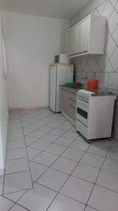 a kitchen with white appliances and a white tiled floor at Residêncial Beatríz in Florianópolis