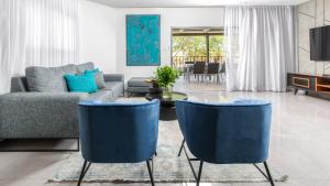sala de estar con sillas azules y sofá en אורה דירות אירוח - הנופש האיכותי ביותר למשפחות, מגוון דירות, en Eilat