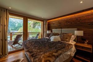 a bedroom with a large bed and a balcony at Sonnhalde II - Luxury Chalet in Saas-Fee
