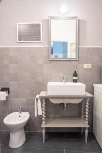 La salle de bains est pourvue d'un lavabo, de toilettes et d'un miroir. dans l'établissement Casa vacanze nel centro storico di Fermo Happy Song, à Fermo