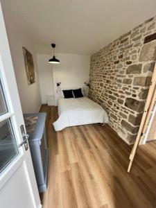 Schlafzimmer mit Ziegelwand und Bett in der Unterkunft Appartement neuf 4pers, remparts in Guérande