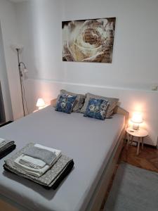 a bedroom with a large white bed with two lamps at Stefan Apartman in Novi Sad