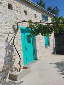 a brick building with a blue door and a tree at Nectar in Lafkos