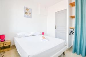 a white bedroom with a white bed and blue curtains at La Canebière - Appart 2 chambres avec terrasse in Marseille