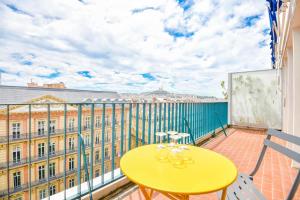einen gelben Tisch und Stühle auf dem Balkon in der Unterkunft La Canebière - Appart 2 chambres avec terrasse in Marseille
