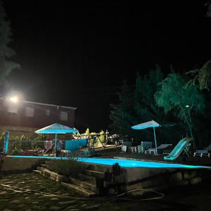 una piscina por la noche con sombrillas en Cabañas Buenache en Buenache de la Sierra