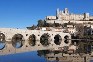 un puente sobre un río con un castillo en el fondo en Petite Maison indépendante., en Béziers