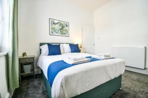 a bedroom with a large bed with blue and white sheets at Lister House in Hartlepool