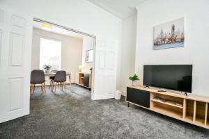 a living room with a flat screen tv and a table at Lister House in Hartlepool
