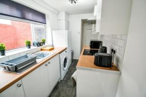 a white kitchen with a sink and a microwave at Lister House in Hartlepool