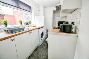 een witte keuken met een wastafel en een wasmachine bij Lister House in Hartlepool