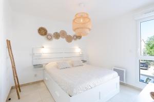 a white bedroom with a bed and a window at Appartement Neuf 4 étoiles - Sunset Lodge, Narbonne Plage in Narbonne