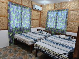 - 2 lits dans une chambre dotée de rideaux bleus dans l'établissement Siquijor Cottage Lynn Candaping B, à Maria
