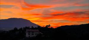 a sunset with a house in front of a mountain at Chambre chez l'habitant "Entre Airs et Montagnes" in Tallard