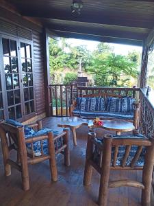 eine Veranda mit Sofas und Tischen auf dem Balkon in der Unterkunft Enzo lodge chambre hibiscus in Papawa