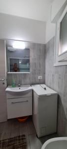 a white bathroom with a sink and a mirror at La Casa del mare in Rosolina Mare