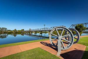 a statue of a wooden wheel next to a river at Home Plus TAREE CBD in Taree