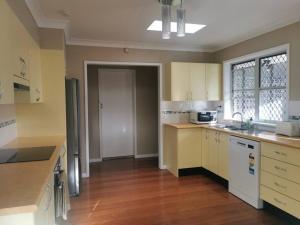 een keuken met witte apparatuur en een houten vloer bij Home Plus TAREE CBD in Taree