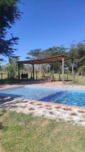 a gazebo with a picnic table and a pool at La Hacienda in Atyrá